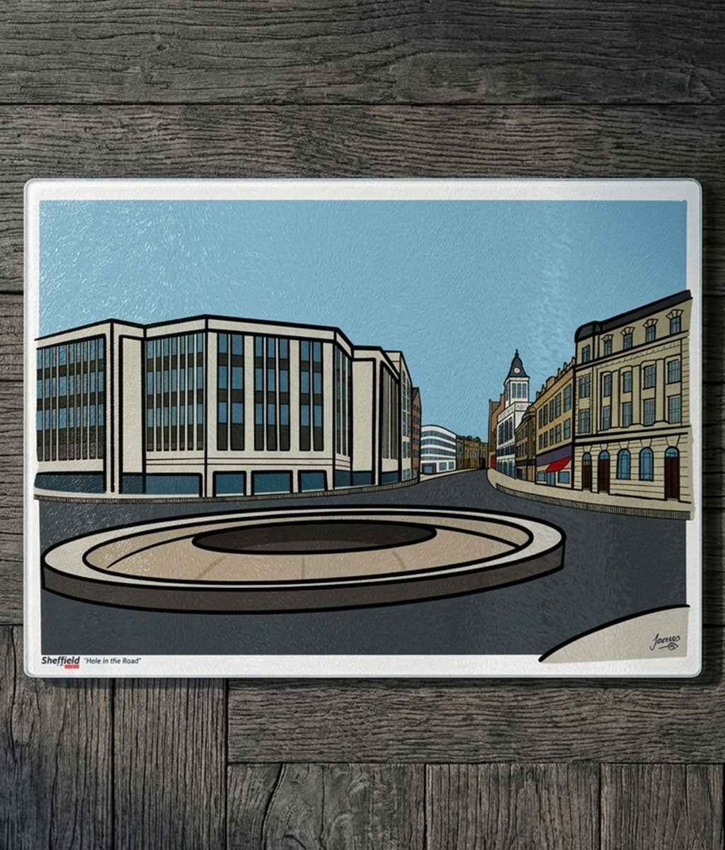 Illustration of a city street with buildings and a roundabout on a  glass chopping board atop a wooden surface