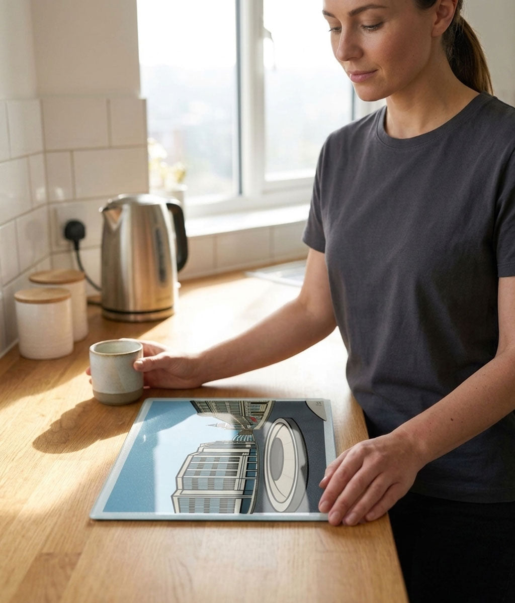 Woman in a kitchen holding a glass chopping board with a coffee cup on the counter