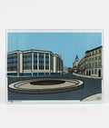Illustration of a city street with buildings and a roundabout on a blue background on a glass chopping board