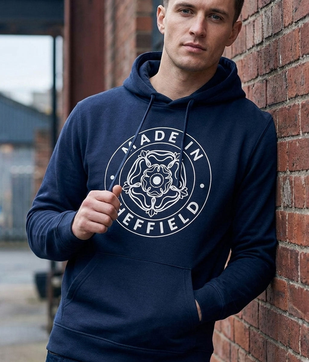 Man wearing a navy hoodie with 'Made in Sheffield' logo against a brick wall.