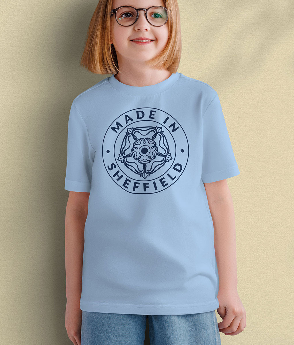 Child wearing a Blue Soul Made in Sheffield kids t-shirt with the exclusive Yorkshire Rose badge design in navy, against a warm yellow background.