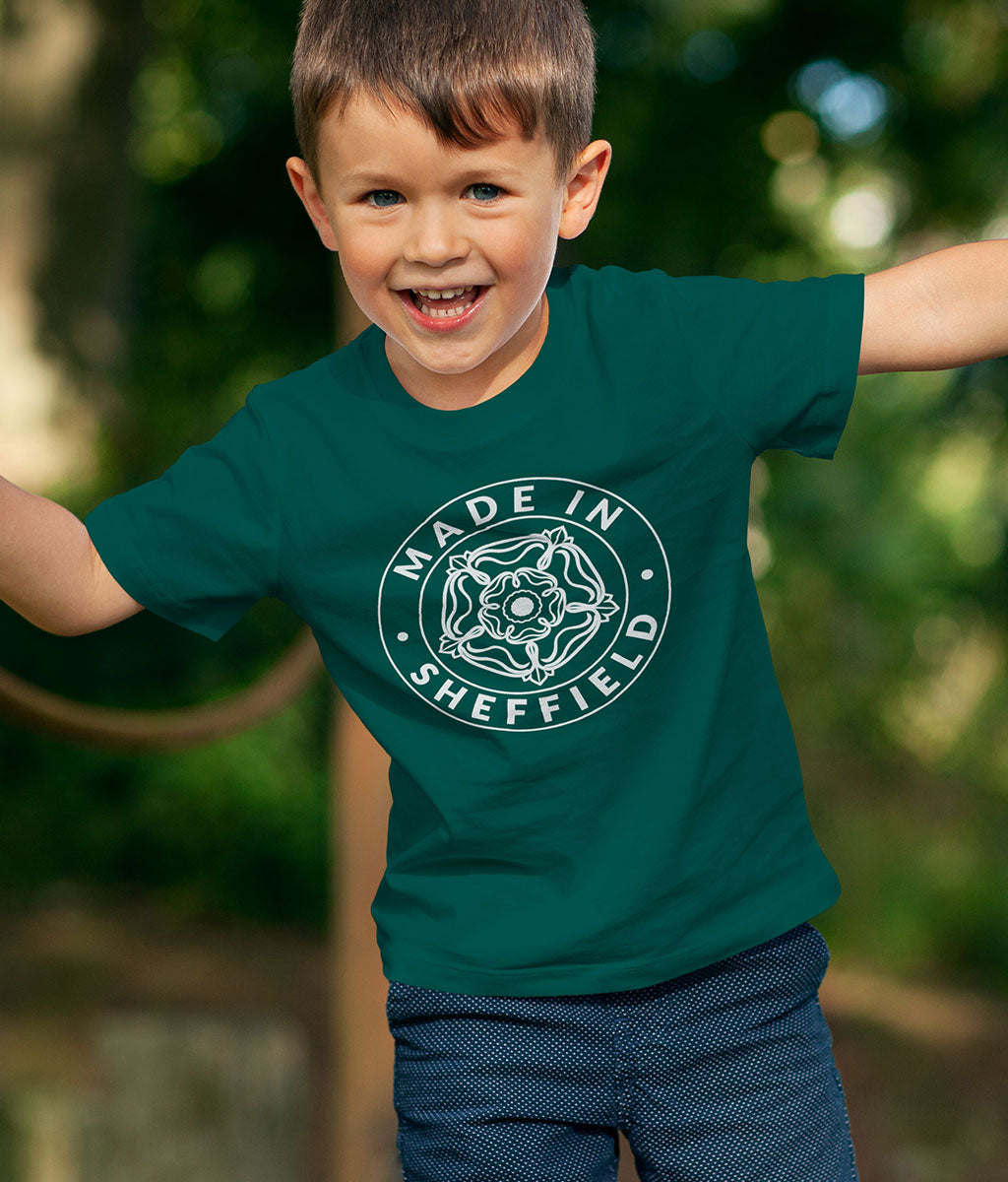 Child wearing a green 'Made in Sheffield' t-shirt with a blurred natural background