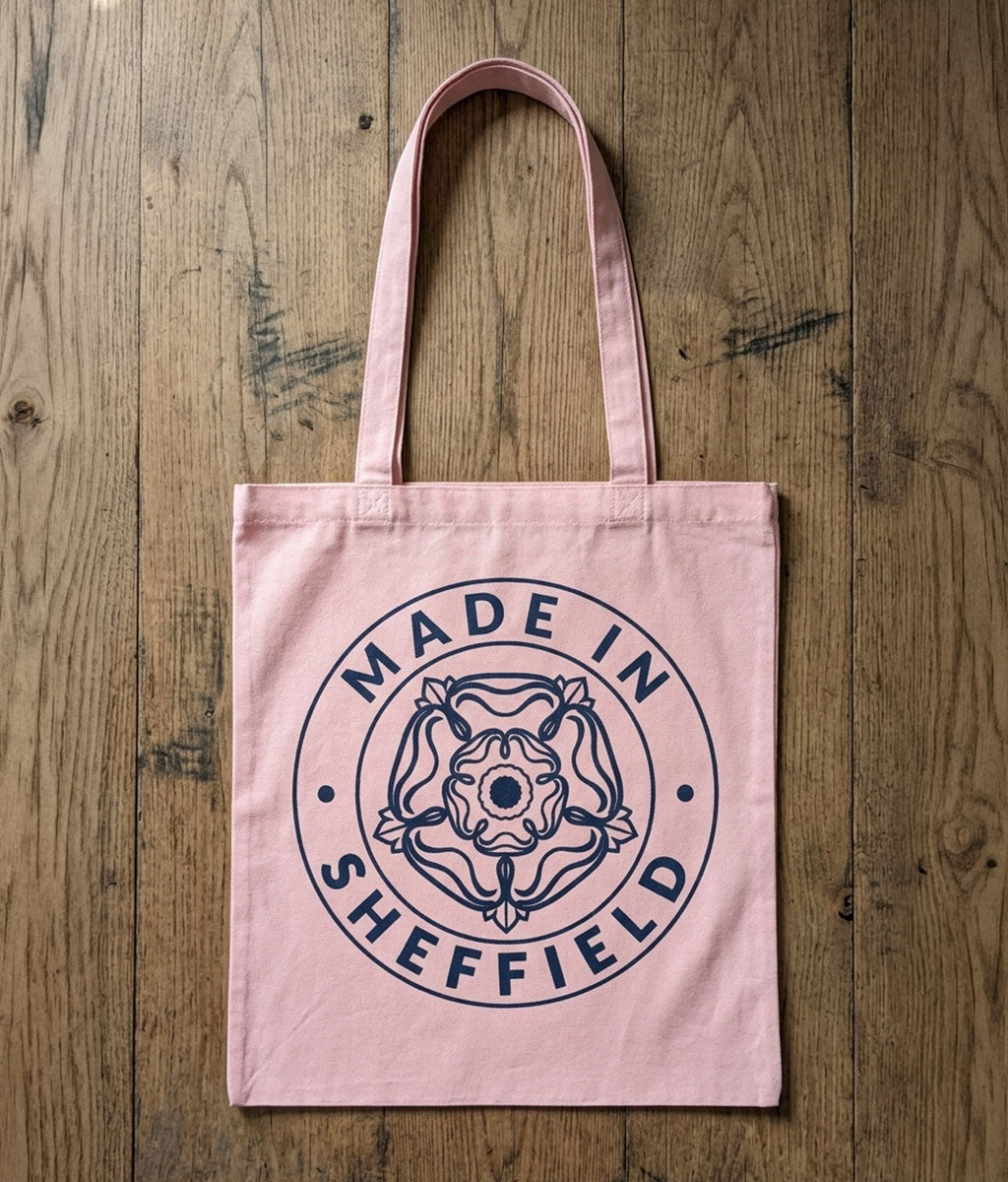 Pink tote bag with 'Made in Sheffield' text on a wooden surface