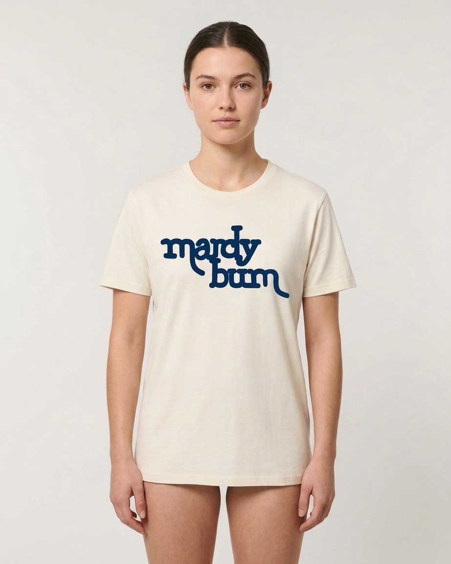 A woman modeling a cream-colored short-sleeve t-shirt with the text 'mardy bum' printed in dark blue across the chest, set against a plain light gray background.