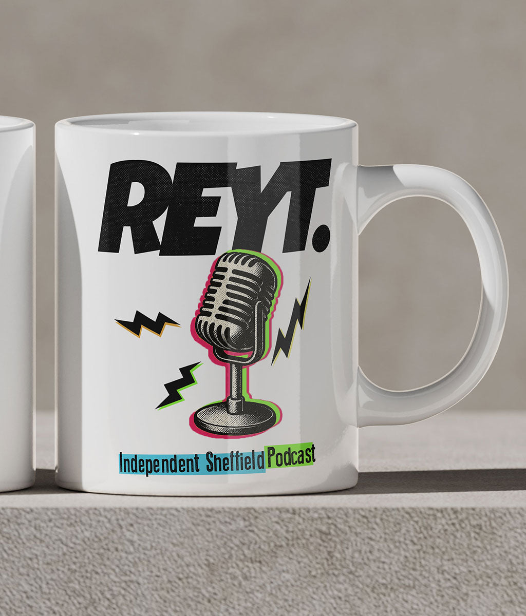 White mug with 'REYT.' and microphone graphic on a gray surface