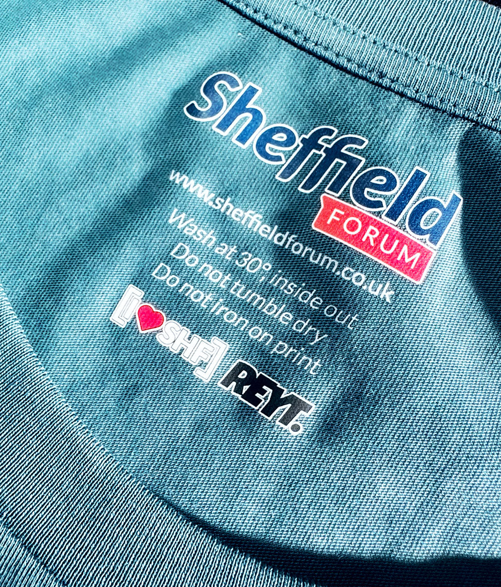 Close-up of a blue garment with 'Sheffield Forum' neck label branding and care instructions.