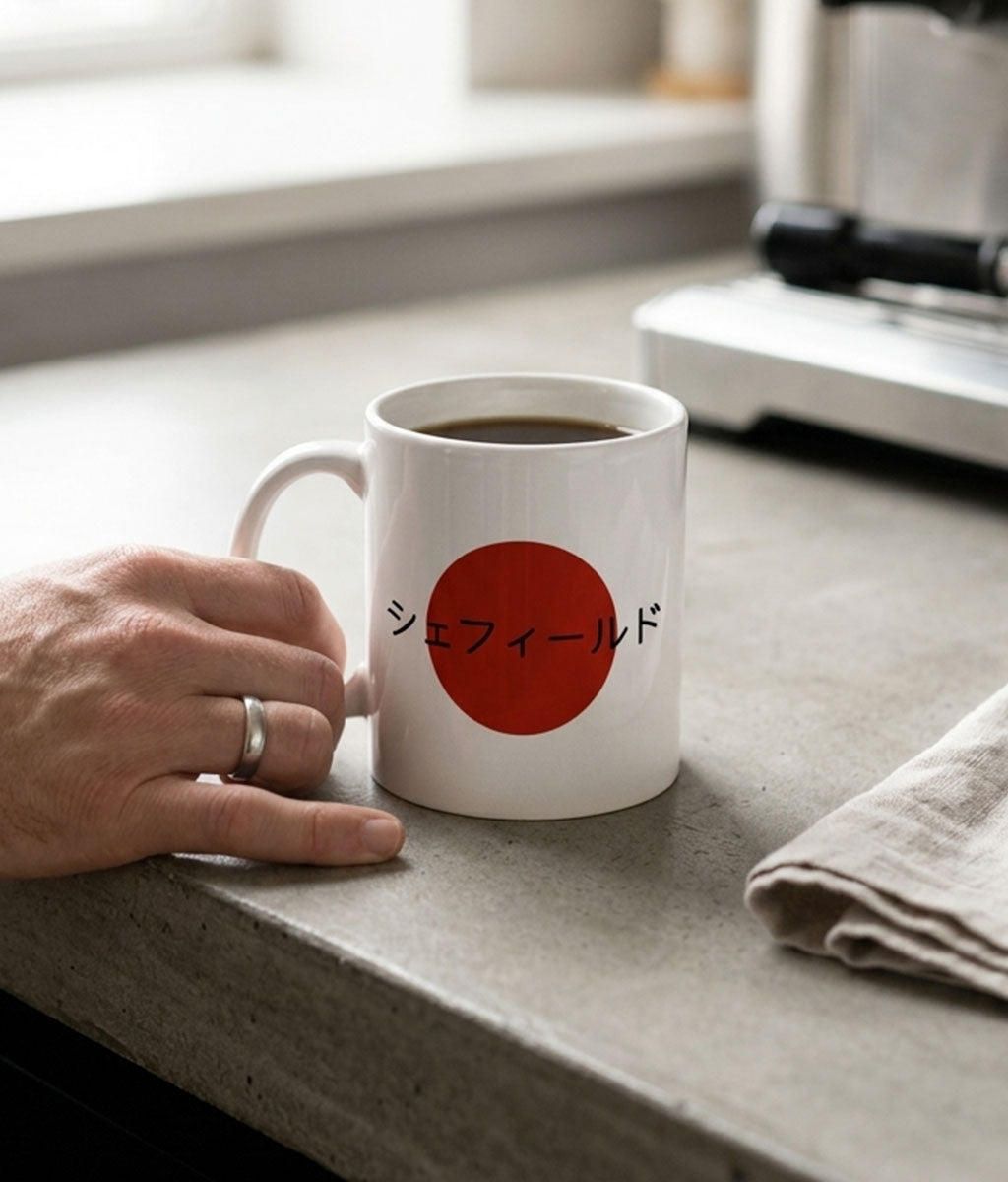 White mug with red circle and Japanese text on a concrete surface, hand holding mug.